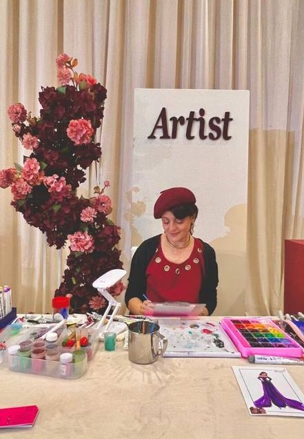 Rania drawing at her artist station with flowers and paints