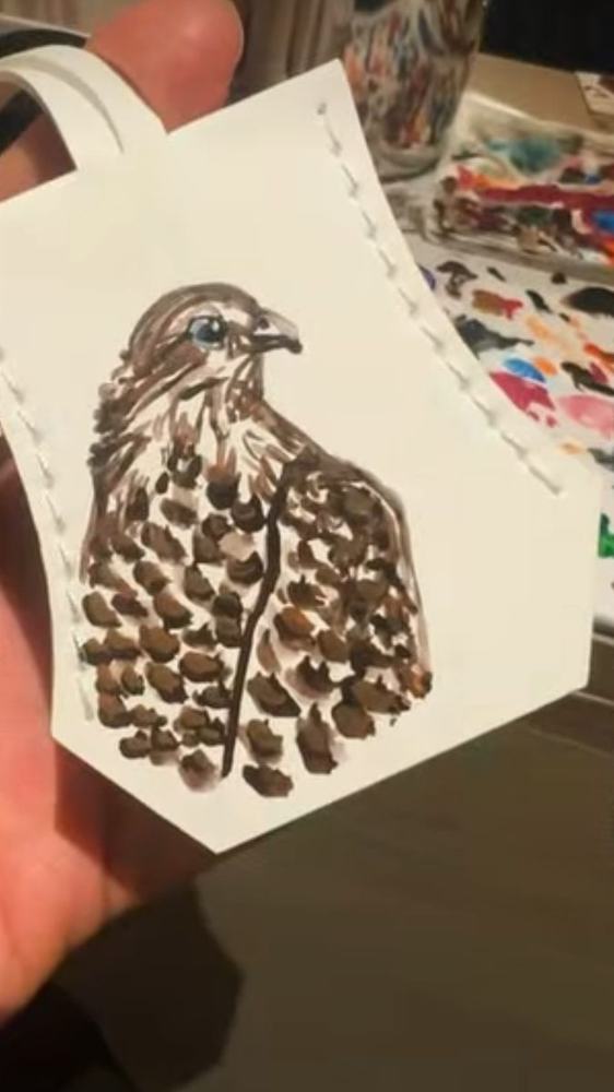 White leather bag tag with a hand-painted falcon