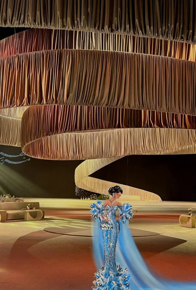 Blue feathered gown illustration in a draped hall
